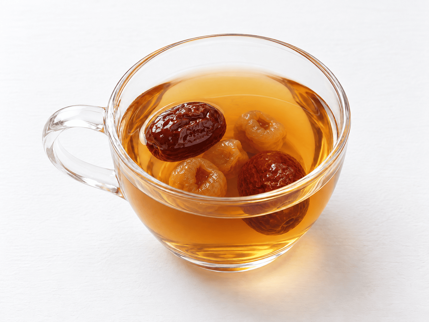 ガラスのカップに入った龍眼の果肉となつめの琥珀色のお茶